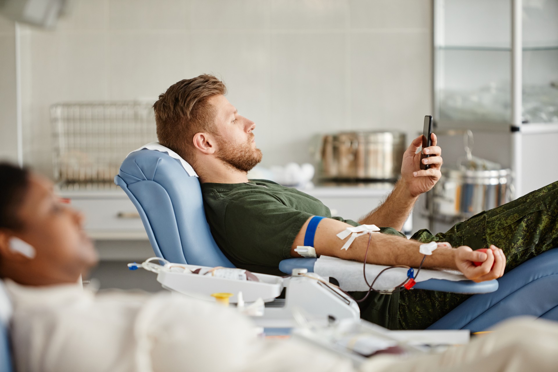 Man using Smartphone in Blood Donation Center Side View