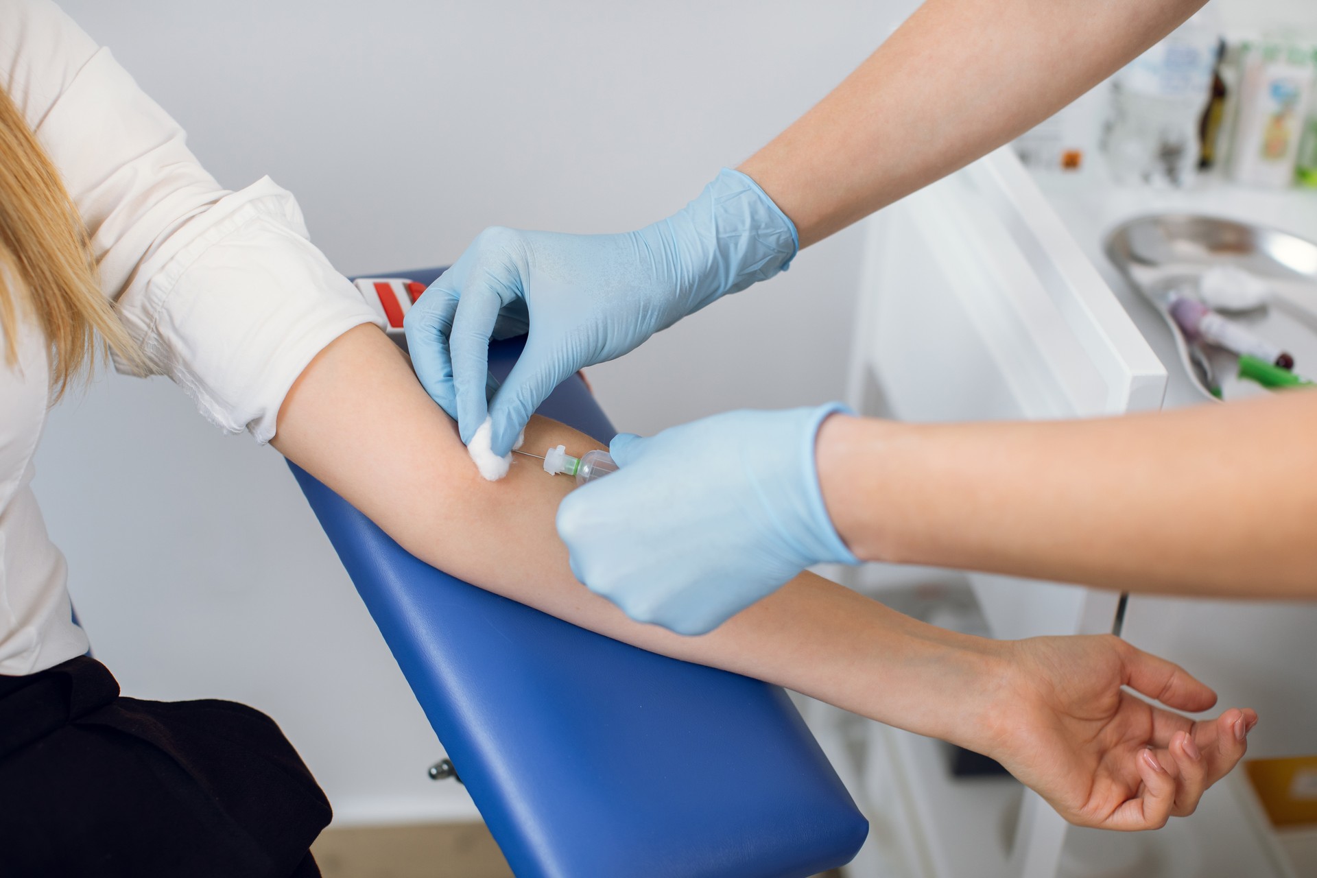 Close up cropped image of unrecognizable doctor and patient. Lab technician nurse pierces the patient's arm vein with needle to collect blood into tube. Blood analysis, donation, dna.